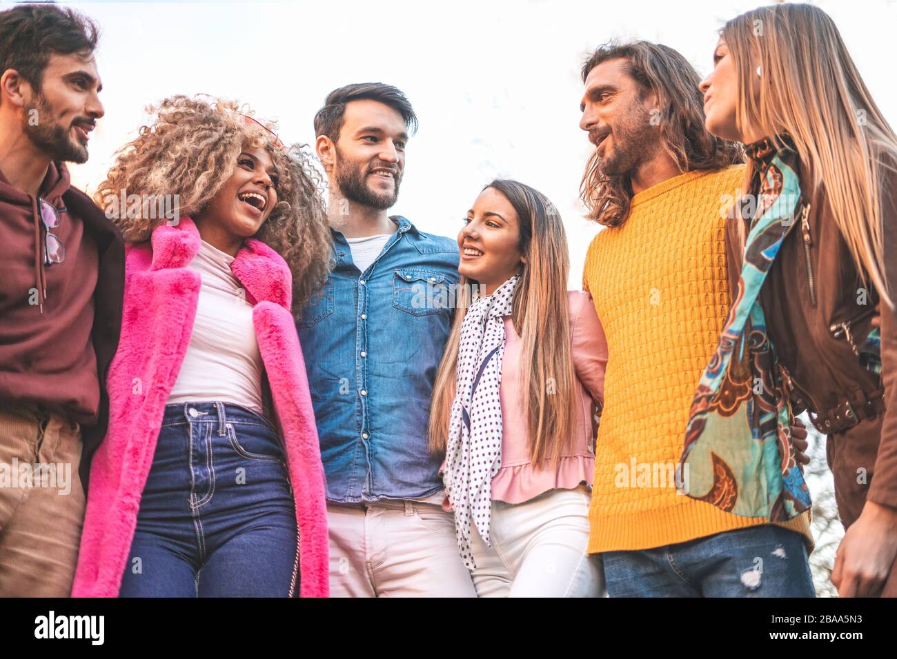 Fröhliche, verschiedene Freunde stehen, sich annehmen, freudige, multirassische Studenten oder Kollegen gruppieren sich in guten freundschaftlichen Beziehungen, die Spaß haben, junge Leute genießen Stockfoto