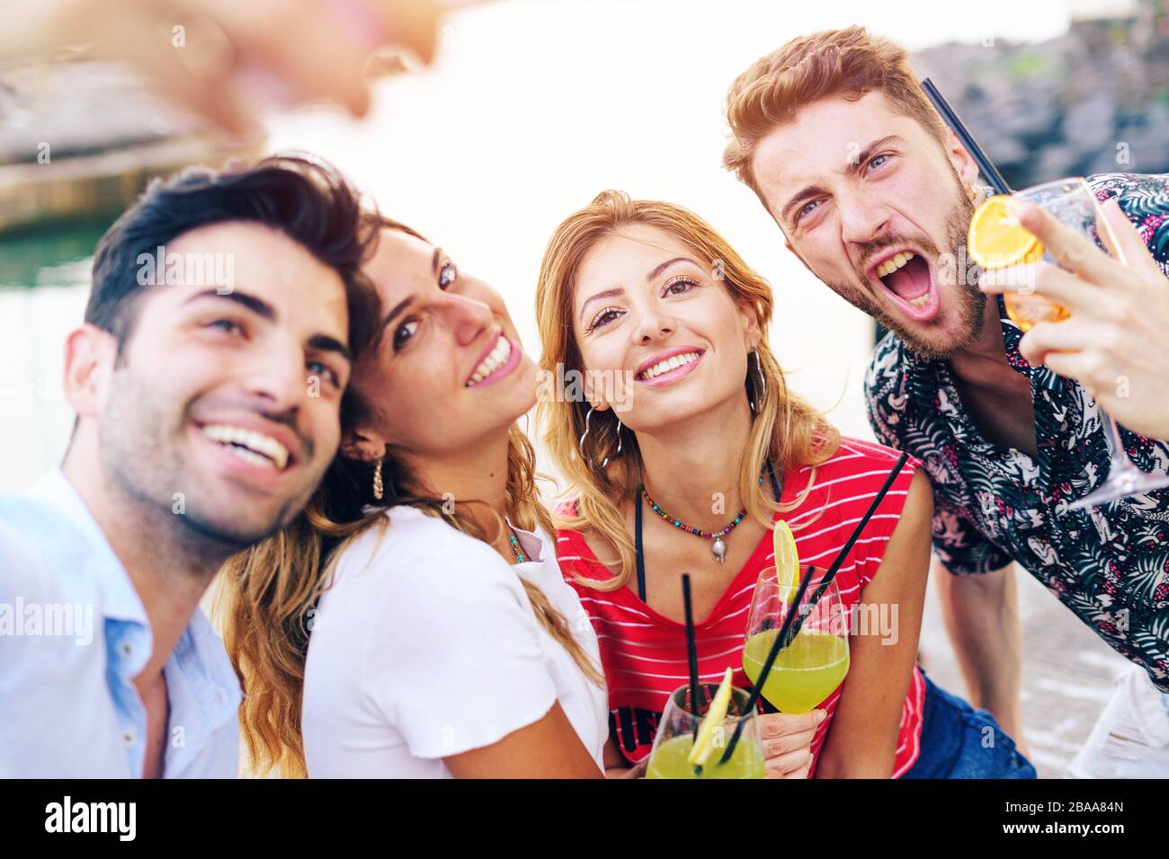 Fröhliche Freunde am Meer, die selfie im Sommer mit bunten Cocktails genießen. Stockfoto
