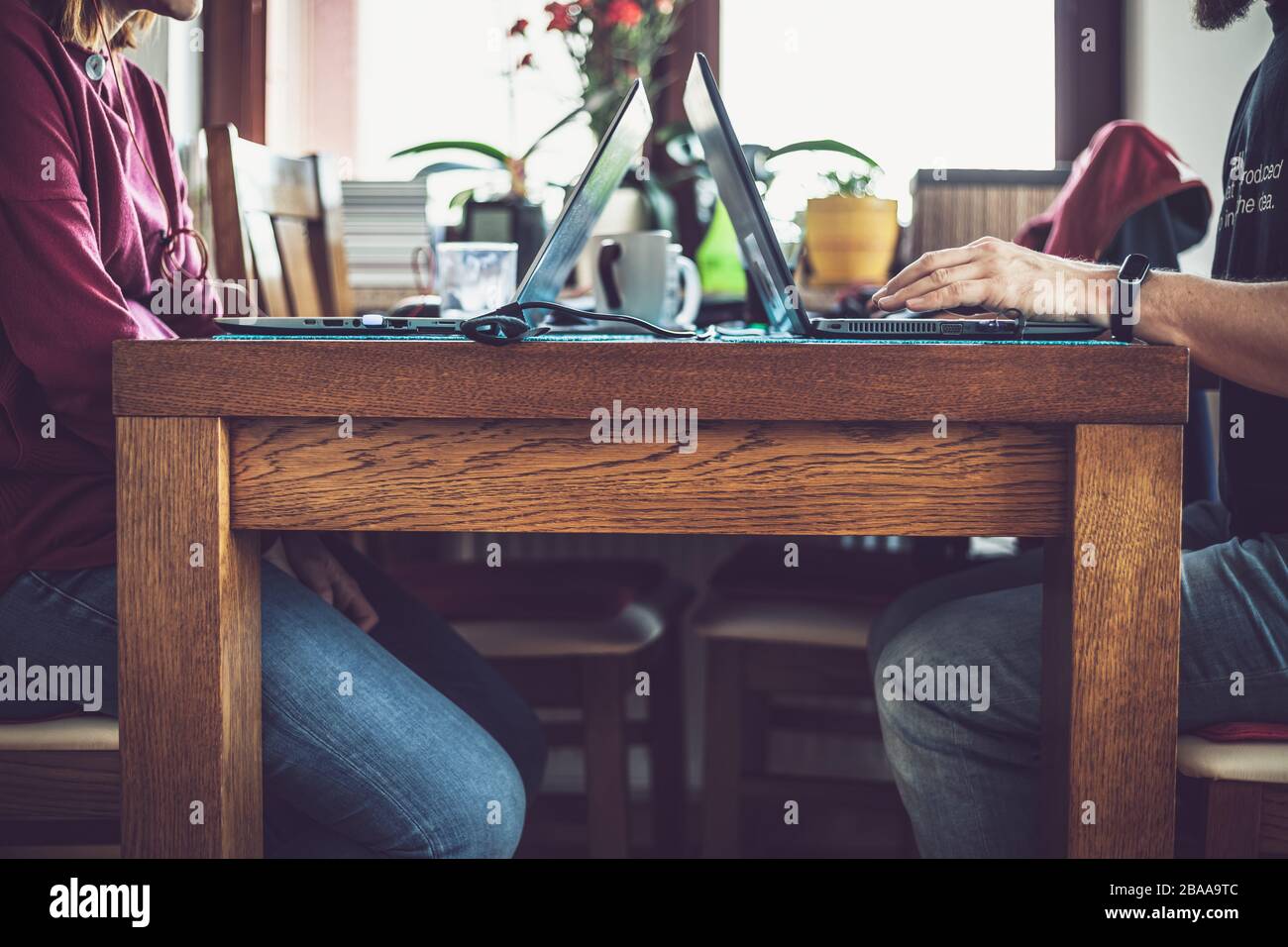 Paare, die während einer Coronavirus-Pandemie von zu Hause arbeiten. Ehrliches Bild von Mann und Frau, die mit ihren Laptops und anderen Sachen in der Nähe an einem Tisch sitzen. Stockfoto