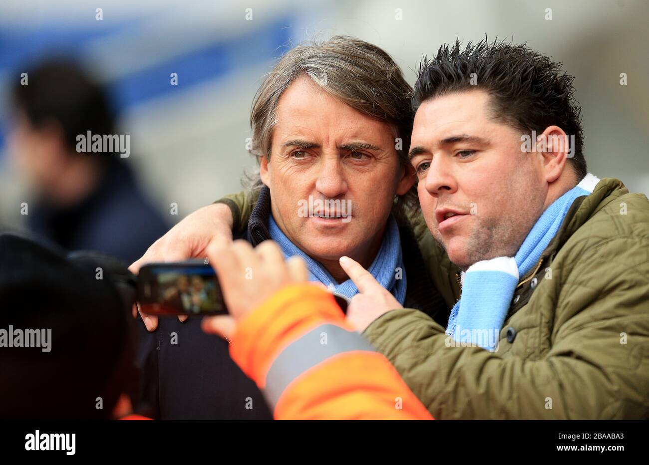 Manchester-City-Manager Roberto Mancini posiert vor dem Spiel für ein Foto mit einem Fan Stockfoto