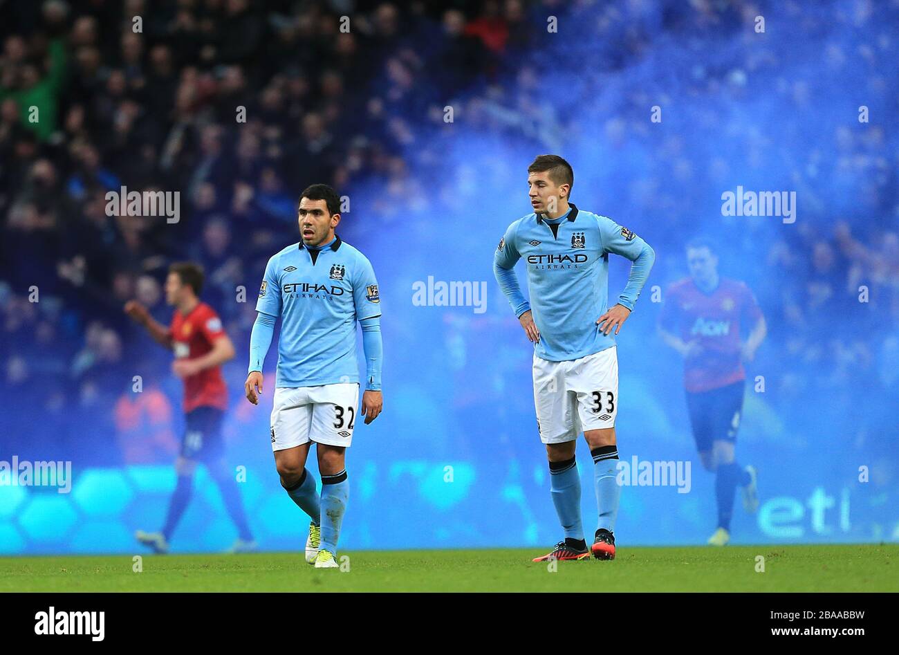 Ein blauer Fleck ist im Hintergrund gesetzt, da Matija Nastasic (rechts) von Manchester City und Carlos Tevez niedergeschlagen wurden, nachdem Manchester United den späten Sieger erzielte Stockfoto
