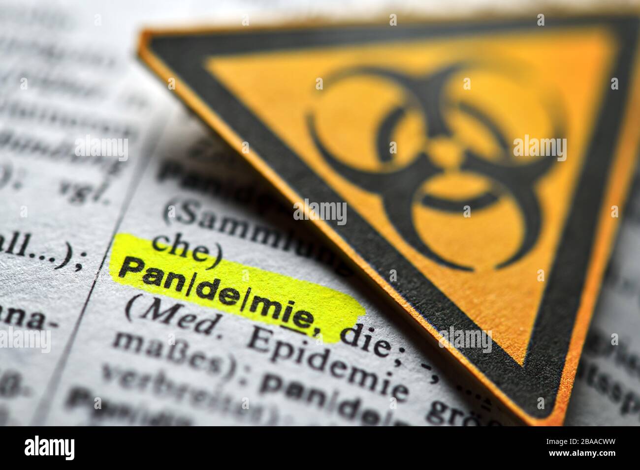 Das Wort Pandemie im Wörterbuch und Biologie Gefahrzeichen, symbolisches Foto Corona Crisis, das Wort Pandemie im Wörterbuch und Biogeährungszeichen, Stockfoto