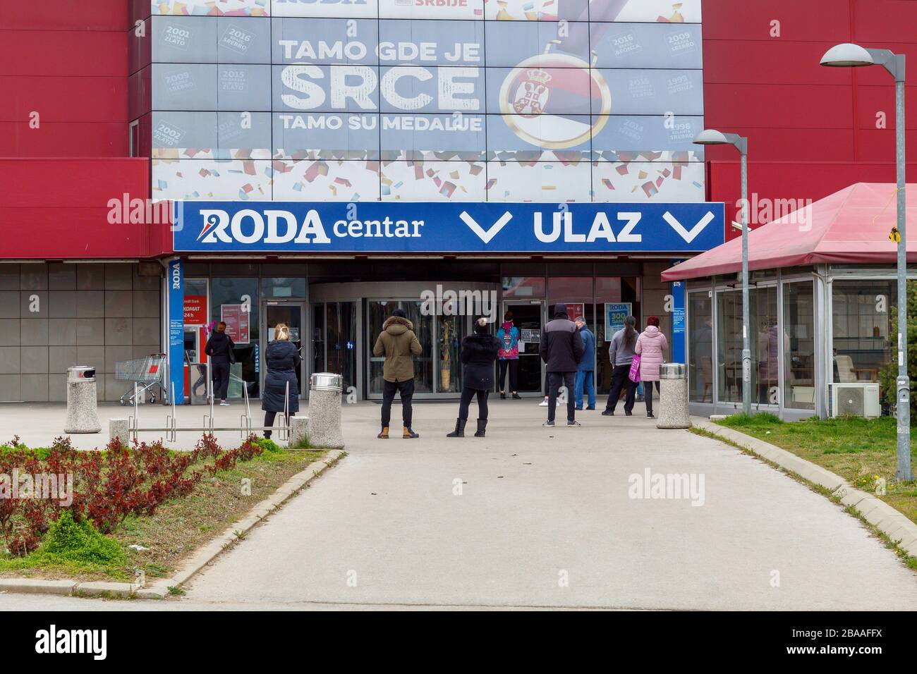 Die Leute warten in der Reihe, während des Corona-Ausbruchs in das Einkaufszentrum Roda in Niš, Serbien, einzudringen Stockfoto