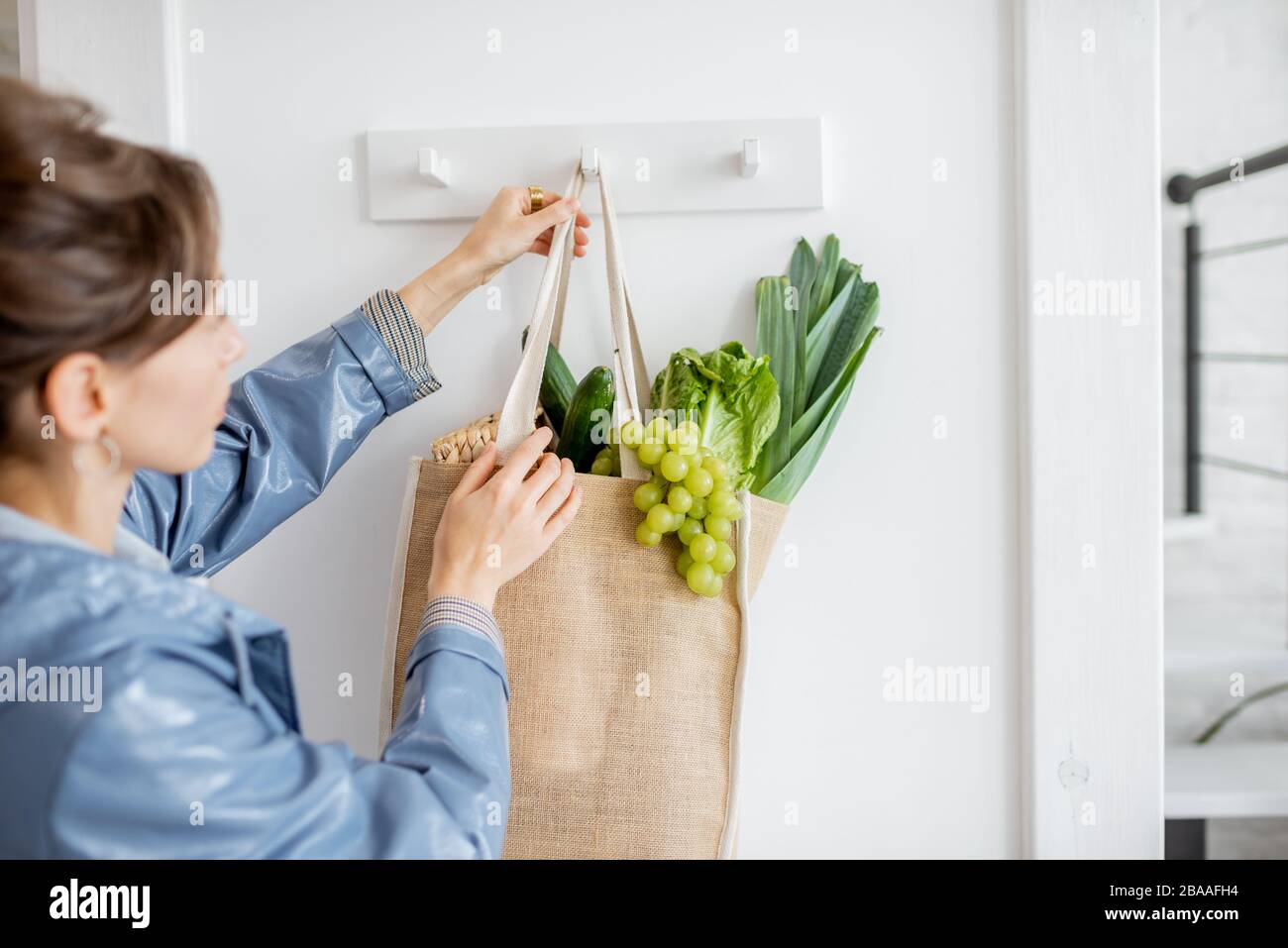 Frau hängende Tasche voller frisches Gemüse und Grüns, während sie nach dem Einkaufen nach Hause kommt Stockfoto