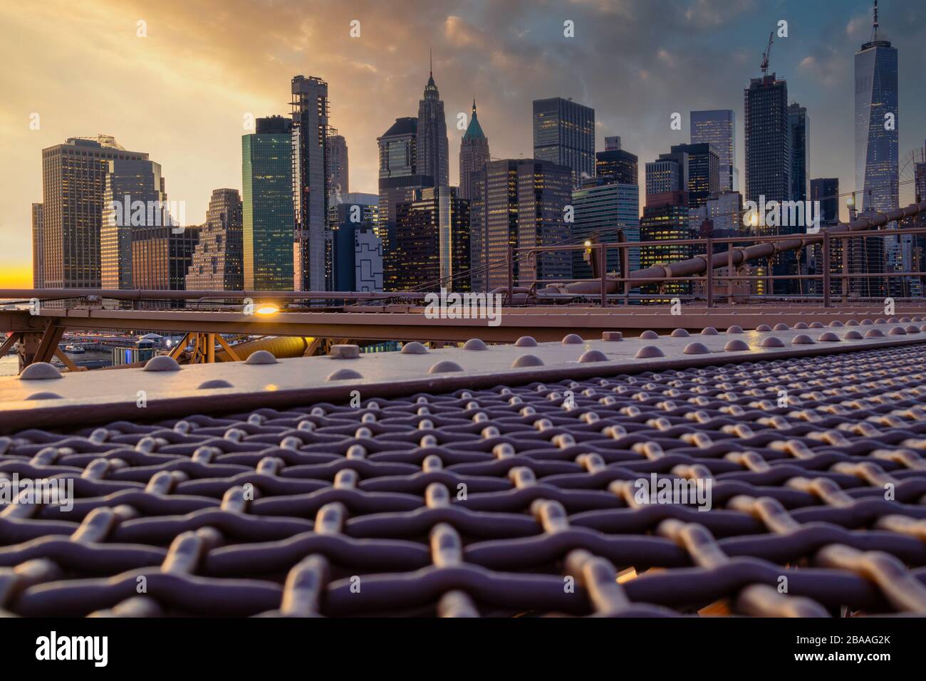 New York Skyline von Brooklyn Bridge bei Sonnenuntergang im Winter mit Wolken am Himmel im Hintergrund Stockfoto