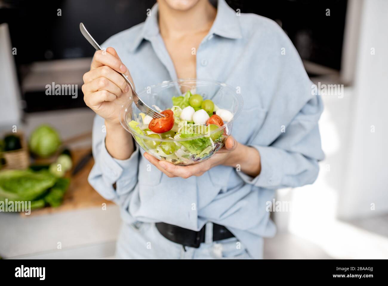 Frau, die zu Hause gesunden Salat in der Küche isst, mit 3/4-Blick ohne Gesicht. Gesundes Essen, Essen und Lifestyle Konzept Stockfoto