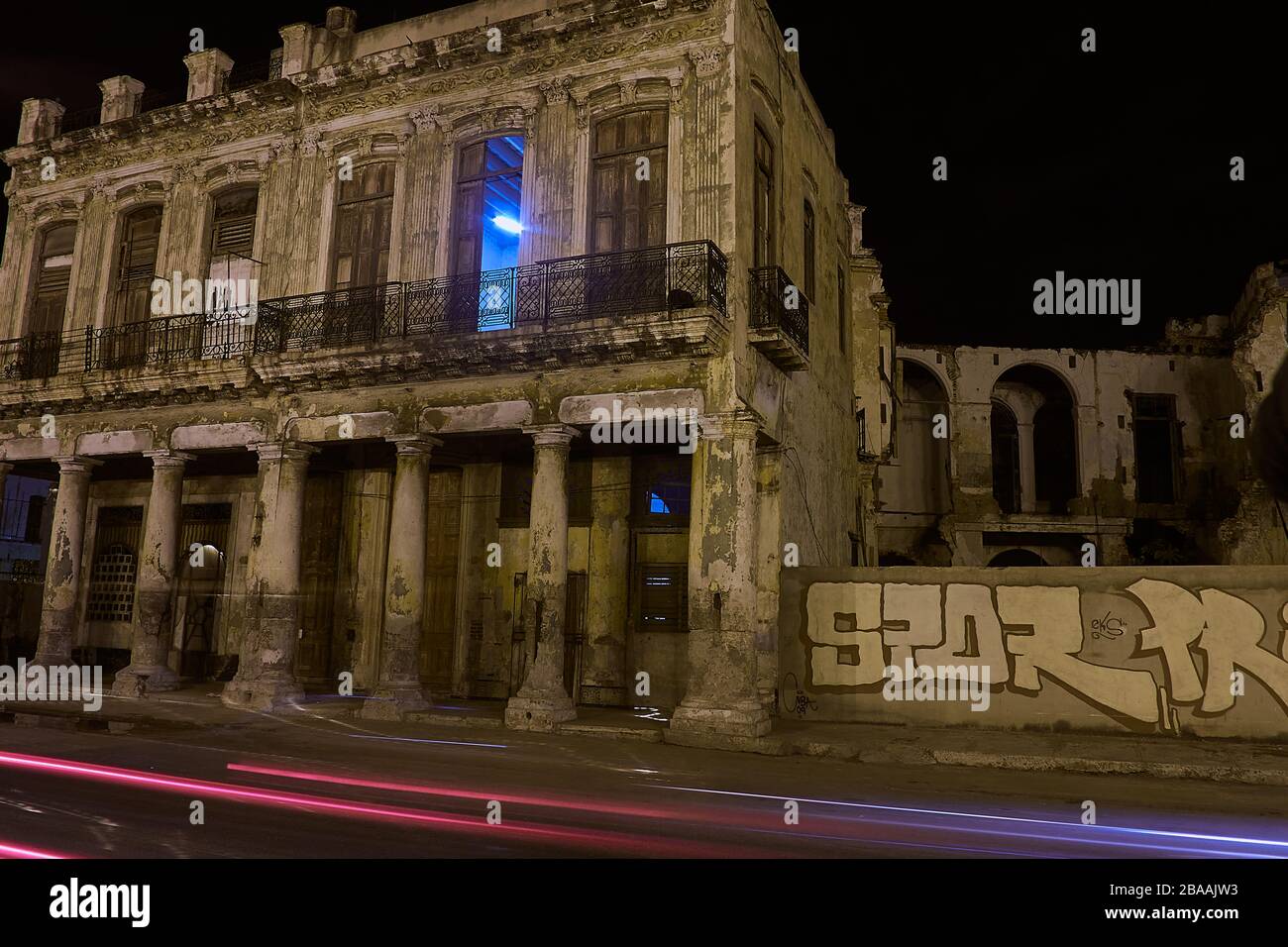 Nachtansicht des beleuchteten Blockgebäudes mit Streifen vorbeifahrender Ampel Stockfoto
