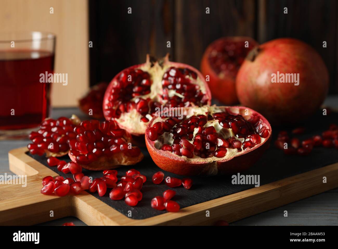 Brett mit Granatapfel und Saft auf Holzgrund, Nahaufnahme Stockfoto