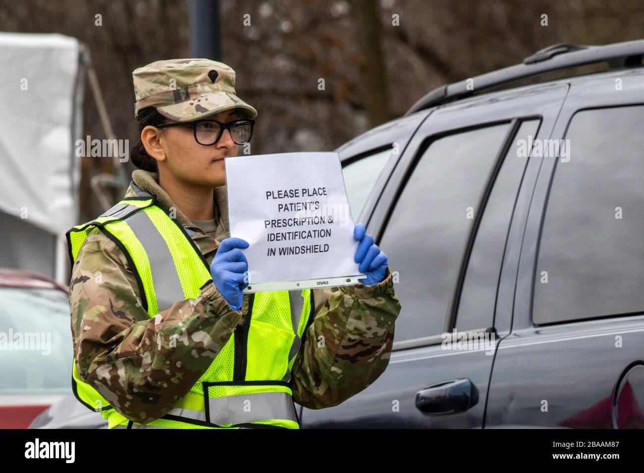 Ein Mitglied der Nationalgarde von New Jersey Air hält Anweisungen an Patienten, die auf Tests an einem COVID-19-gemeinschaftsbasierten Teststandort an der Kean University am 25. März 2020 in Union, New Jersey warten. Stockfoto