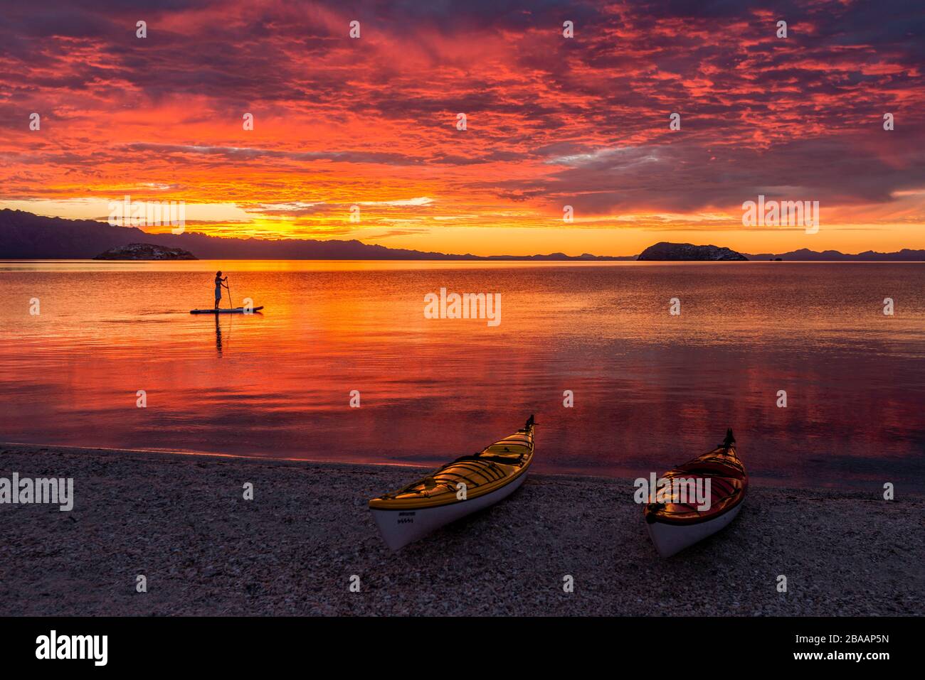 Kajaks am Strand und Paddel-Boarding im Golf von Kalifornien bei Sonnenaufgang, Baja California sur, Mexiko Stockfoto