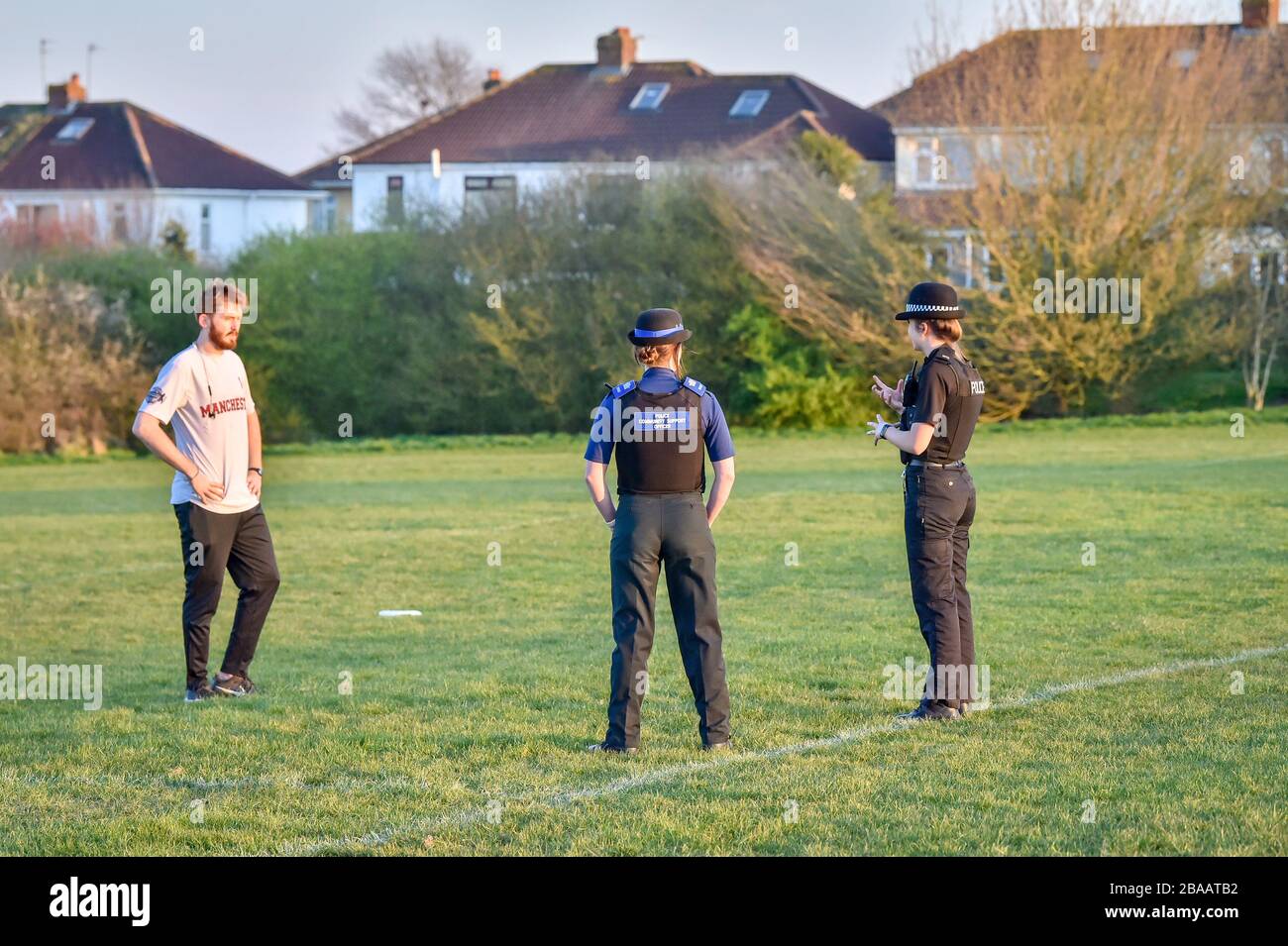 Die Polizisten von Avon und Somerset unterhalten sich mit einem Mann, der in einem Park in Bristol trainiert, wo sie die Sperrregeln für Coronavirus patrouillieren und durchsetzen. Stockfoto