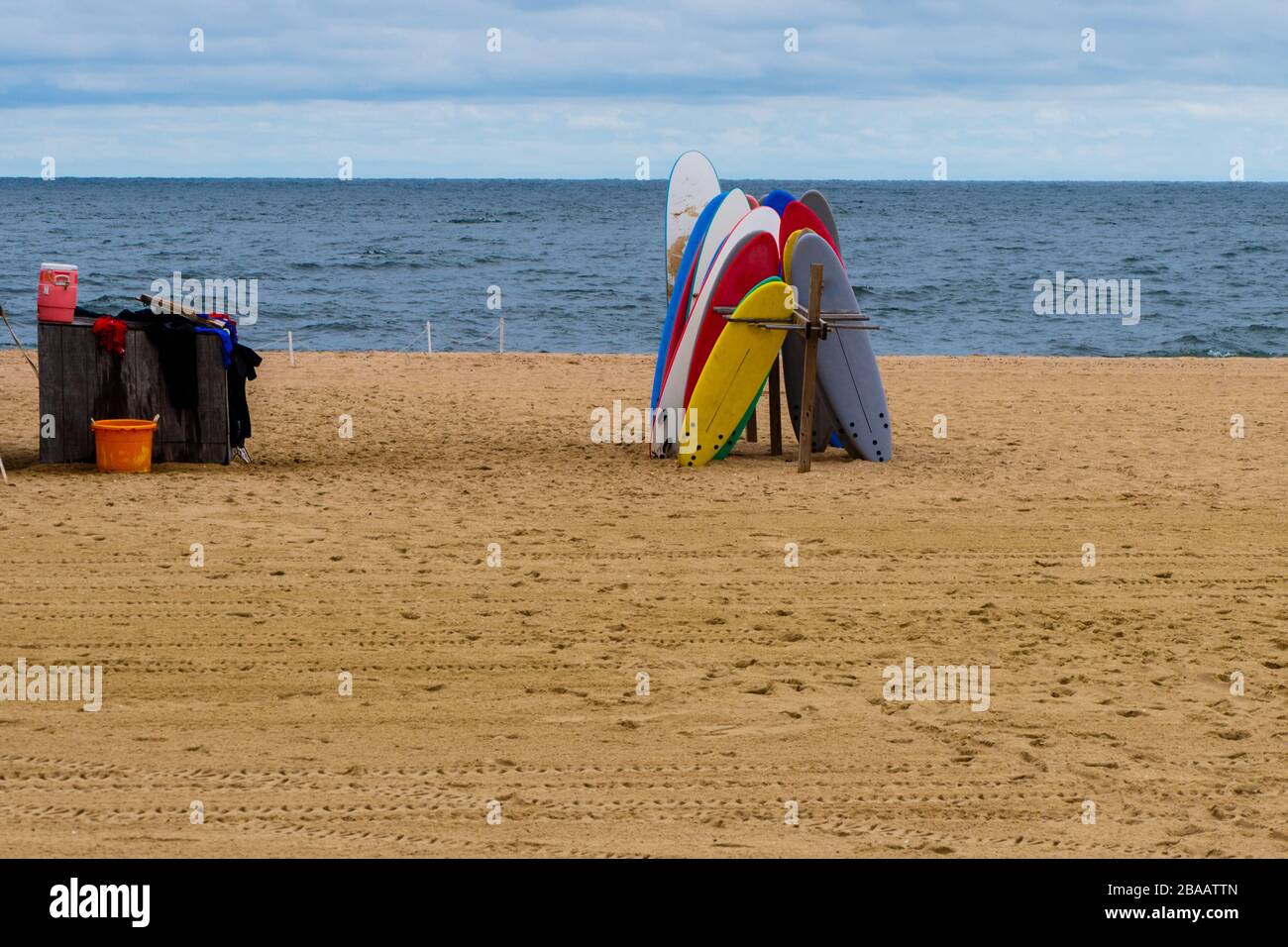 Bunte Surfbretter stehen längs an einem leeren Strand zusammen Stockfoto