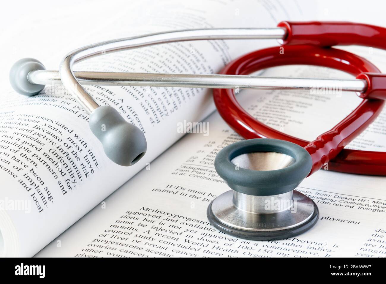 Ein rotes Stethoskop auf einem offenen medizinischen Lehrbuch Stockfoto