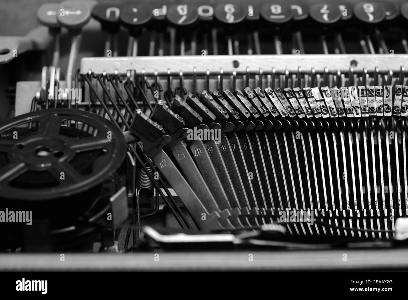 Mechanismus und Tastatur einer alten Schreibmaschine mit einer Filmspule.in Schwarz-Weiß-Bild Stockfoto