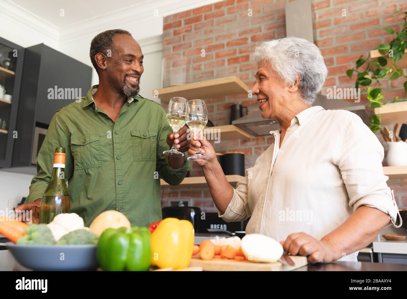 Älteres afroamerikanisches Paar, das in der Küche toastt Stockfoto