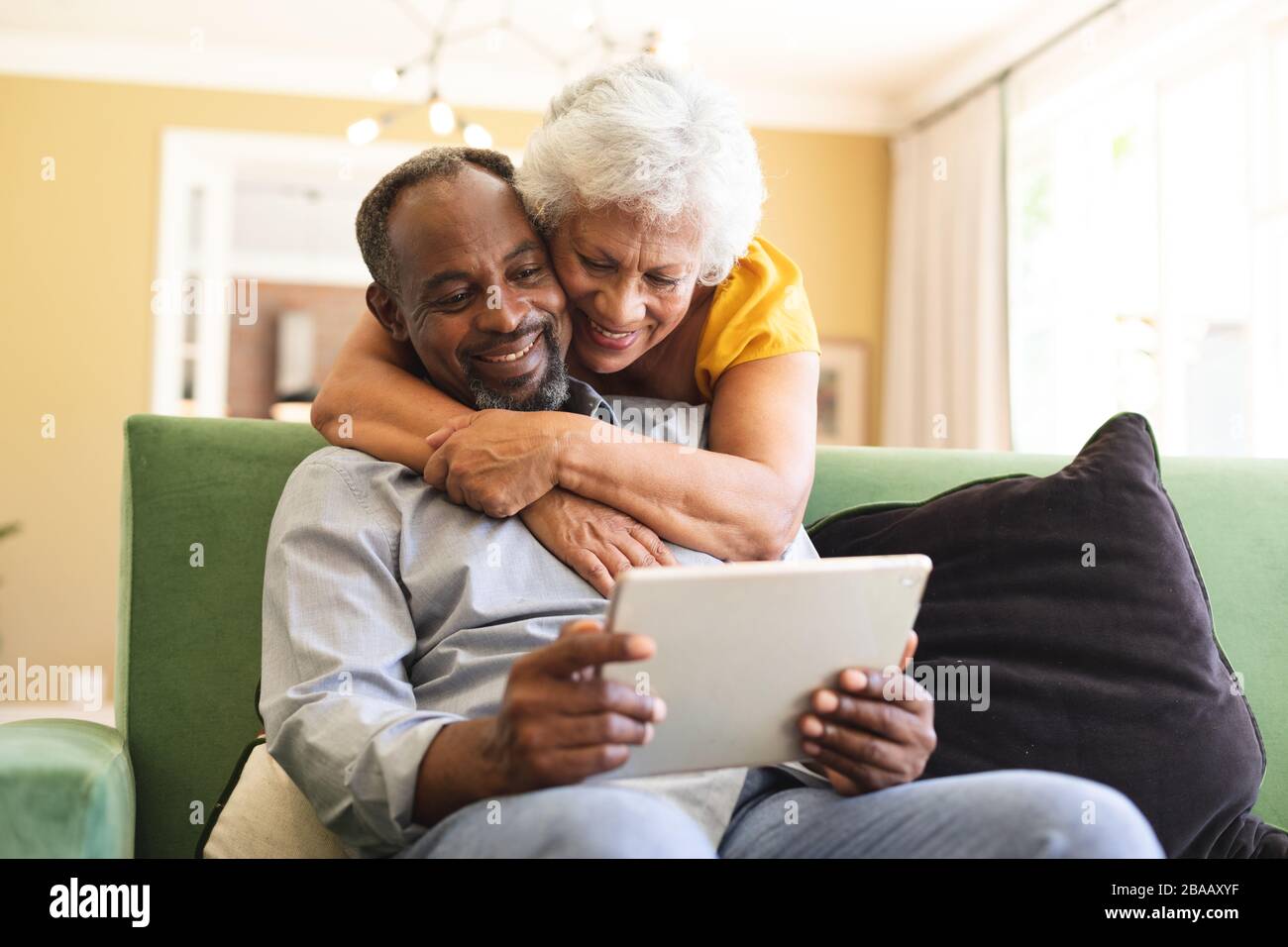 Älteres afroamerikanisches Paar kuscheln und benutzen Laptop in einer Kandare Stockfoto