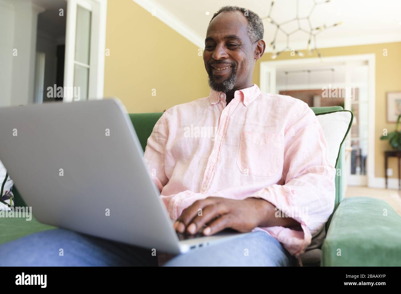 Ein ranghoher afroamerikanischer Mann, der seinen Laptop in einer Kanape sitzend verwendet Stockfoto