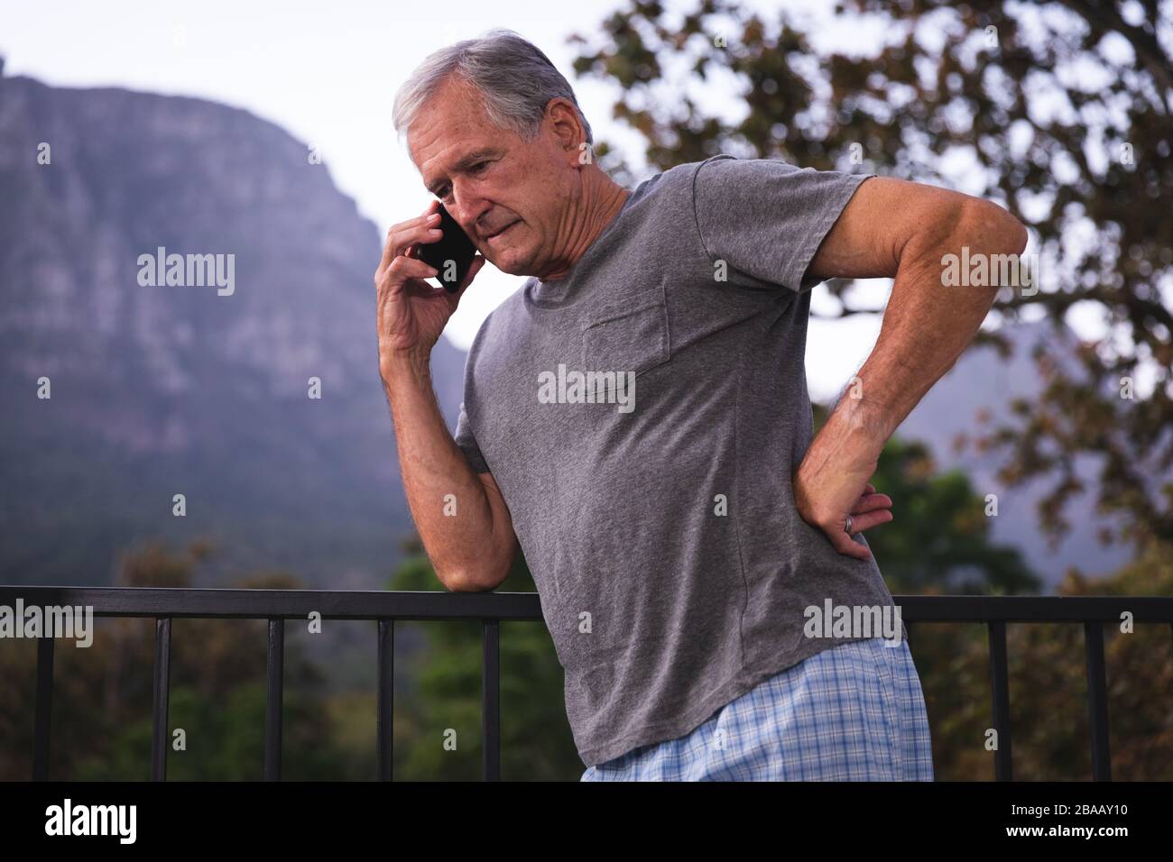 Kaukasischer Senior ruft jemanden zu Hause auf seinem Telefon an Stockfoto