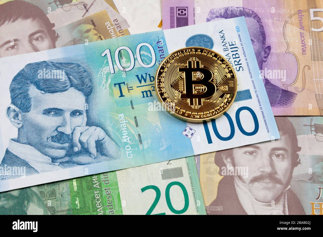 Nahaufnahme einer goldenen Bitcoin-Münze auf einem Stapel serbischer Dinar-Banknoten. Stockfoto