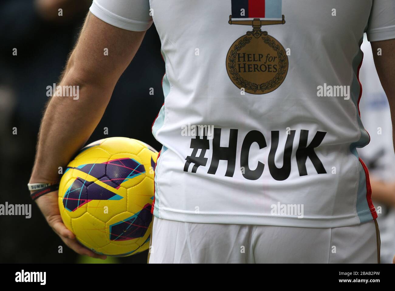 Detail eines Mannes, der den Matchball mit einem T-Shirt "Hilfe für Helden" hält, vor dem Anpfiff Stockfoto