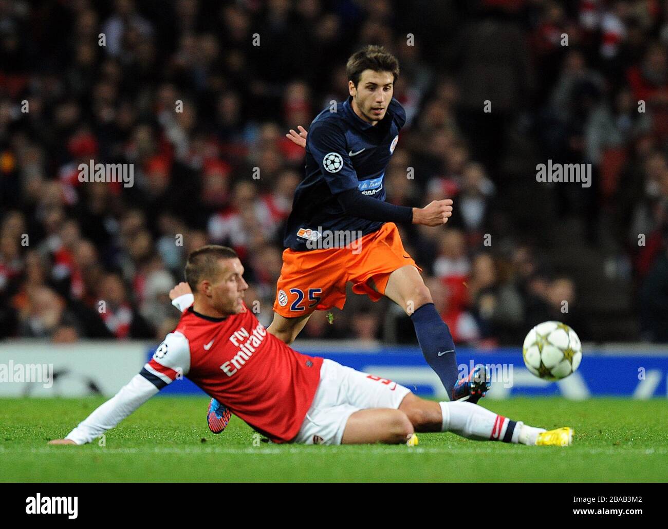 Arsenals Lukas Podolski (links) rutscht ein, um Montpelliers Mathieu Deplagne herauszufordern Stockfoto