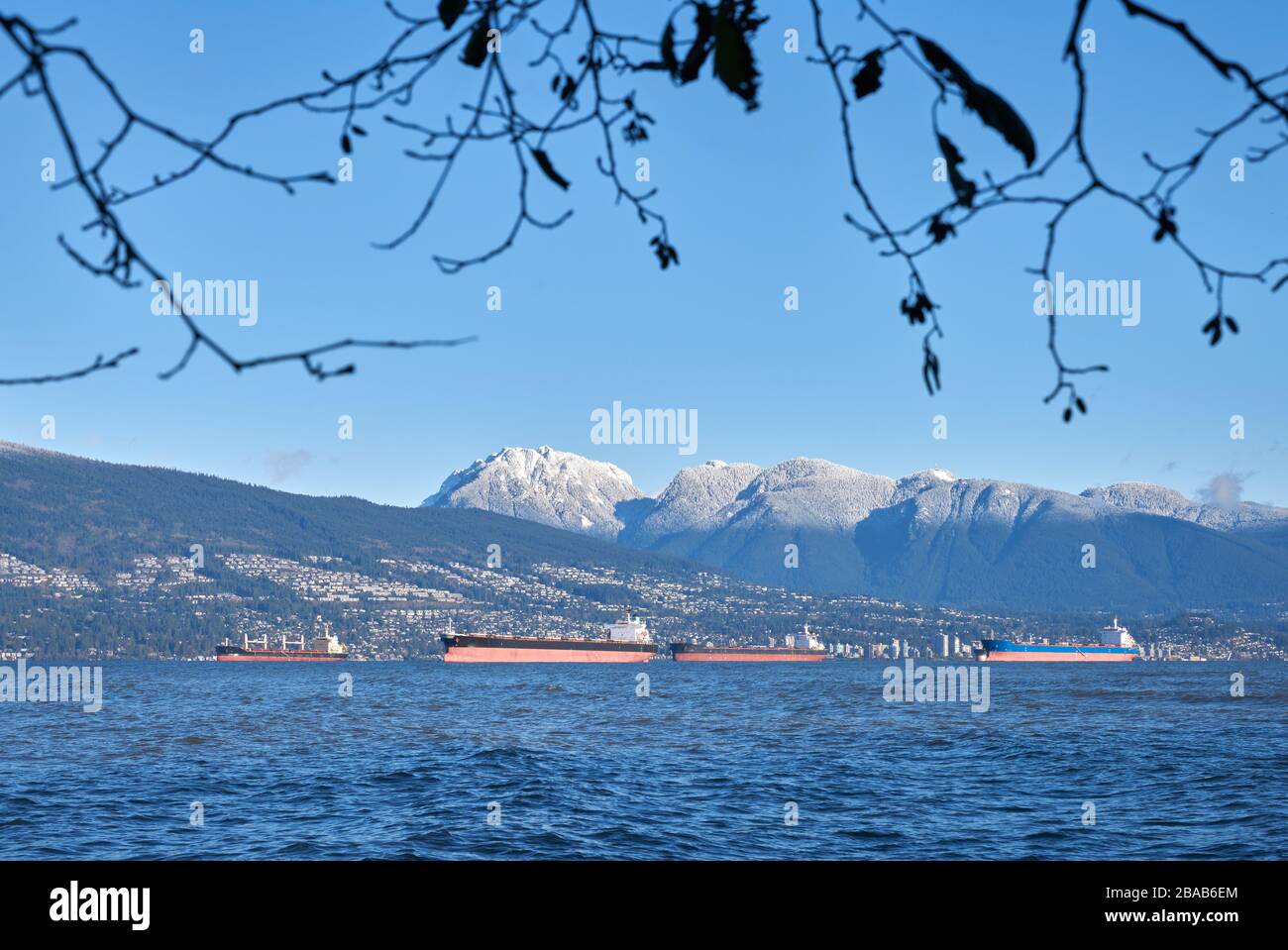 English Bay Frachters und Coast Mountains. Die Coast Mountains hinter English Bay Frachters, Vancouver. Stockfoto