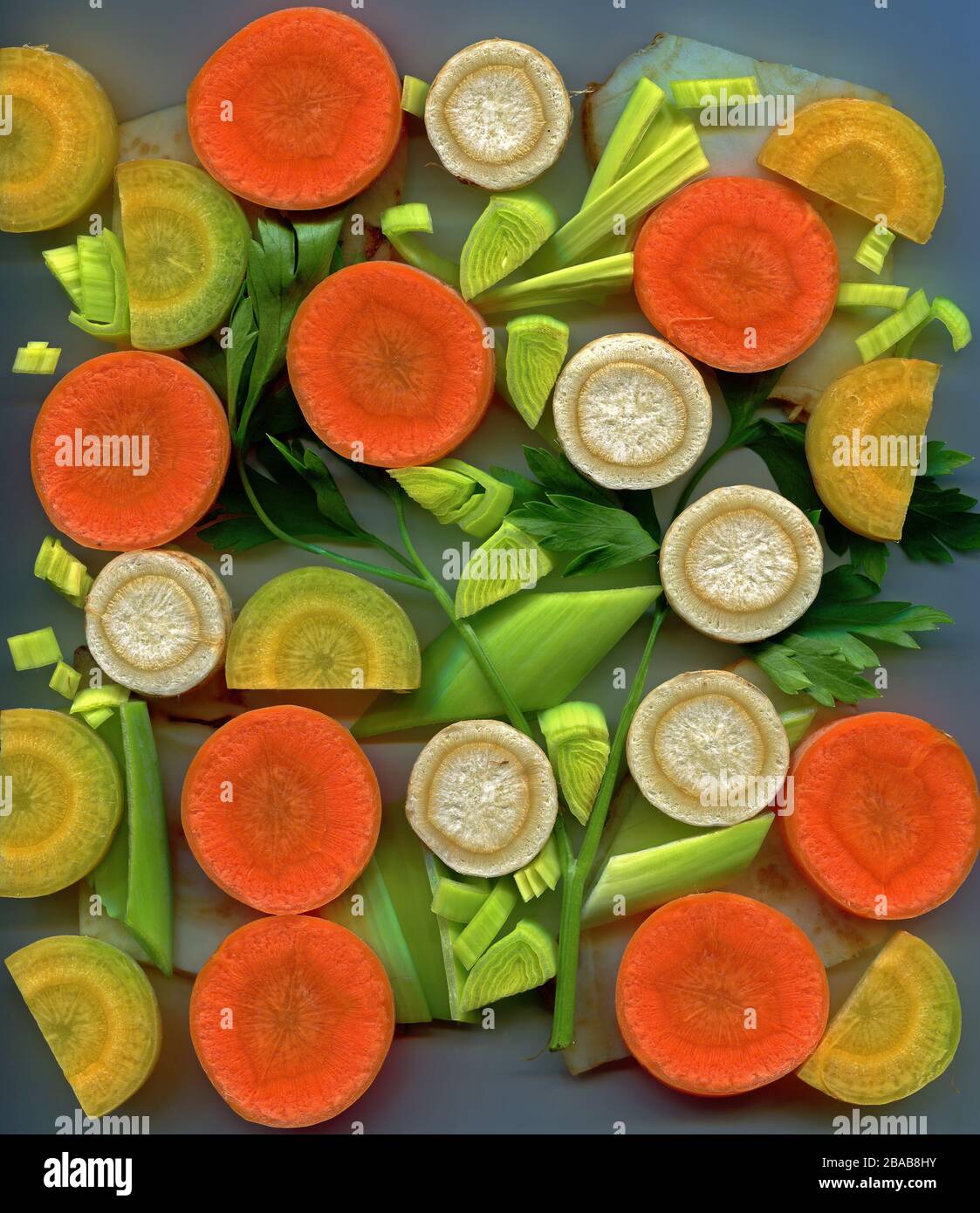 Suppengrün aus orangefarbenen Karotten, Lauch, Petersilienwurzel und gelben Karotten schneiden Stockfoto