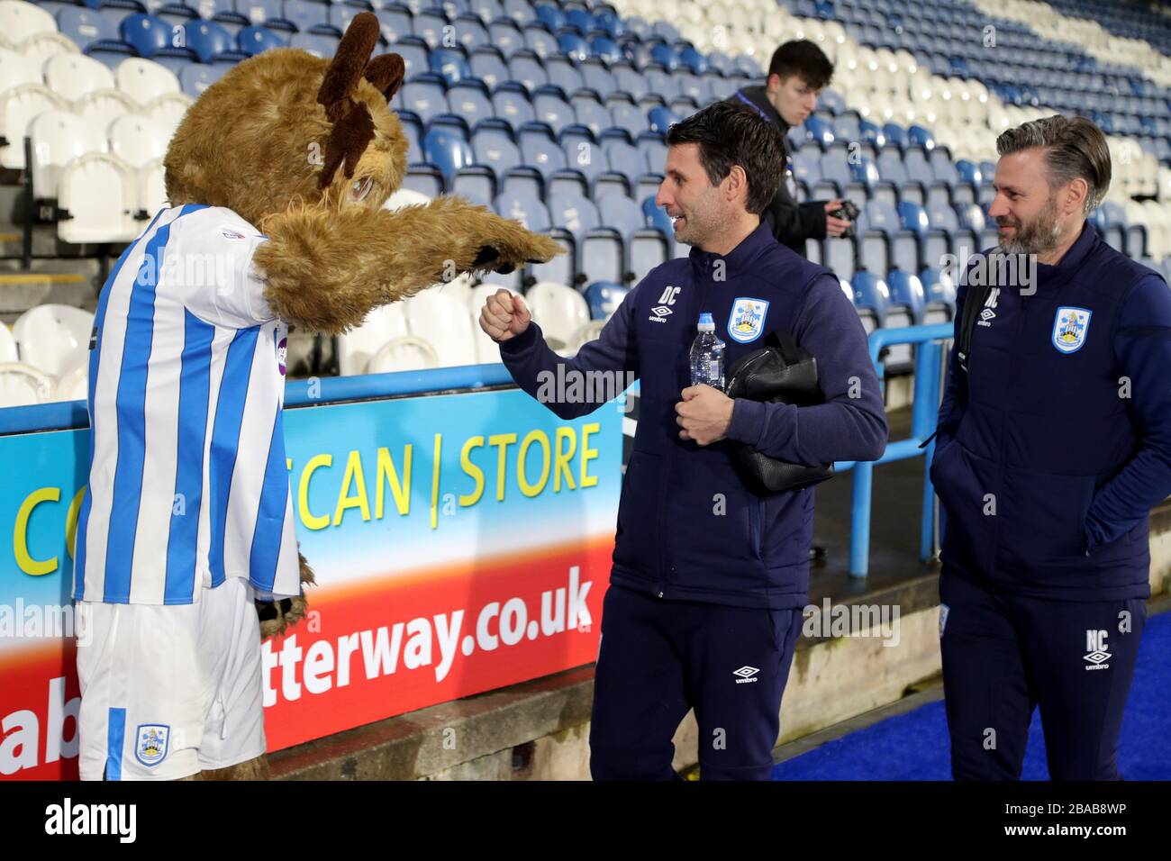 Huddersfield Town Manager Danny Cowley (Center) begrüßt das Vereinsmaskottchen, als er im John Smith's Stadium ankommt Stockfoto