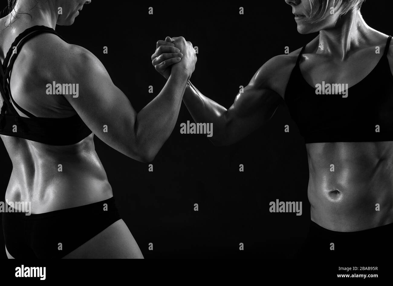 Zwei weibliche Bodybuilder bewaffnen das Ringen vor schwarzem Hintergrund Stockfoto