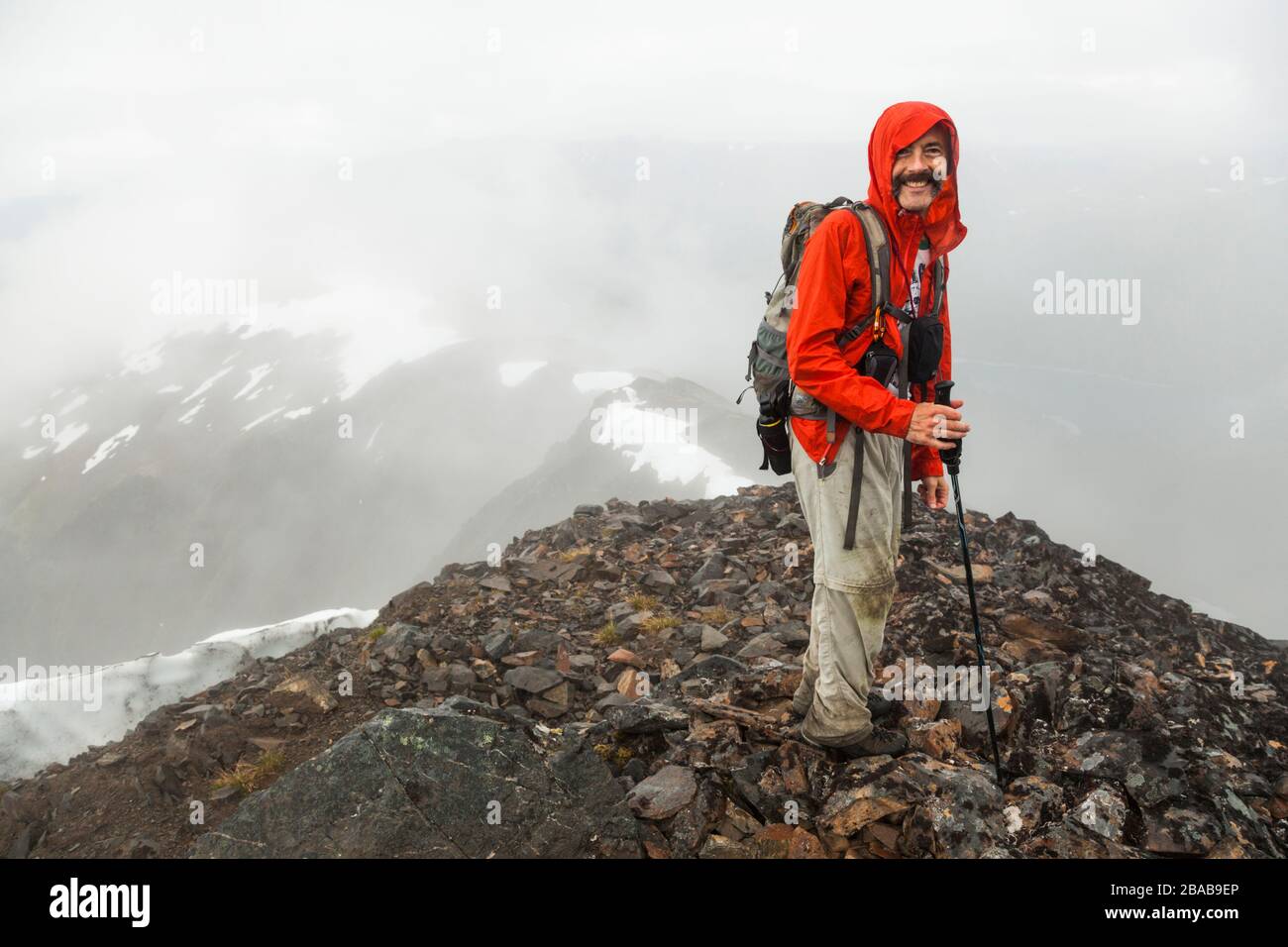 Ein Mann steht unter Wolken auf dem Gipfel des Cooper Mountain, Kenai-Halbinsel, Alaska. Stockfoto