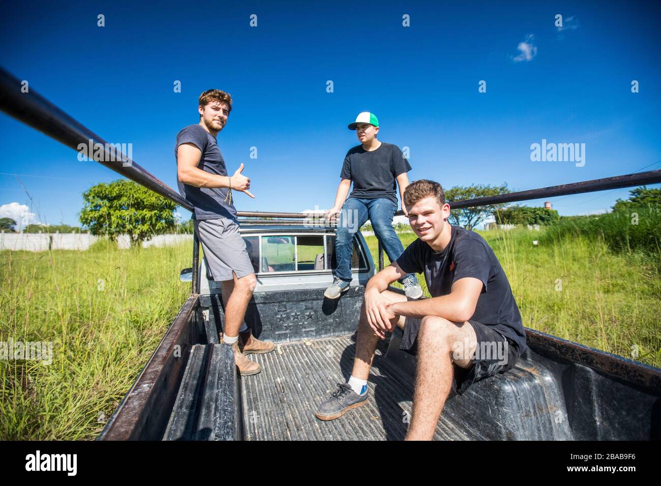 Drei junge Männer fahren durch Feld in hinter 4x4 LKW. Stockfoto