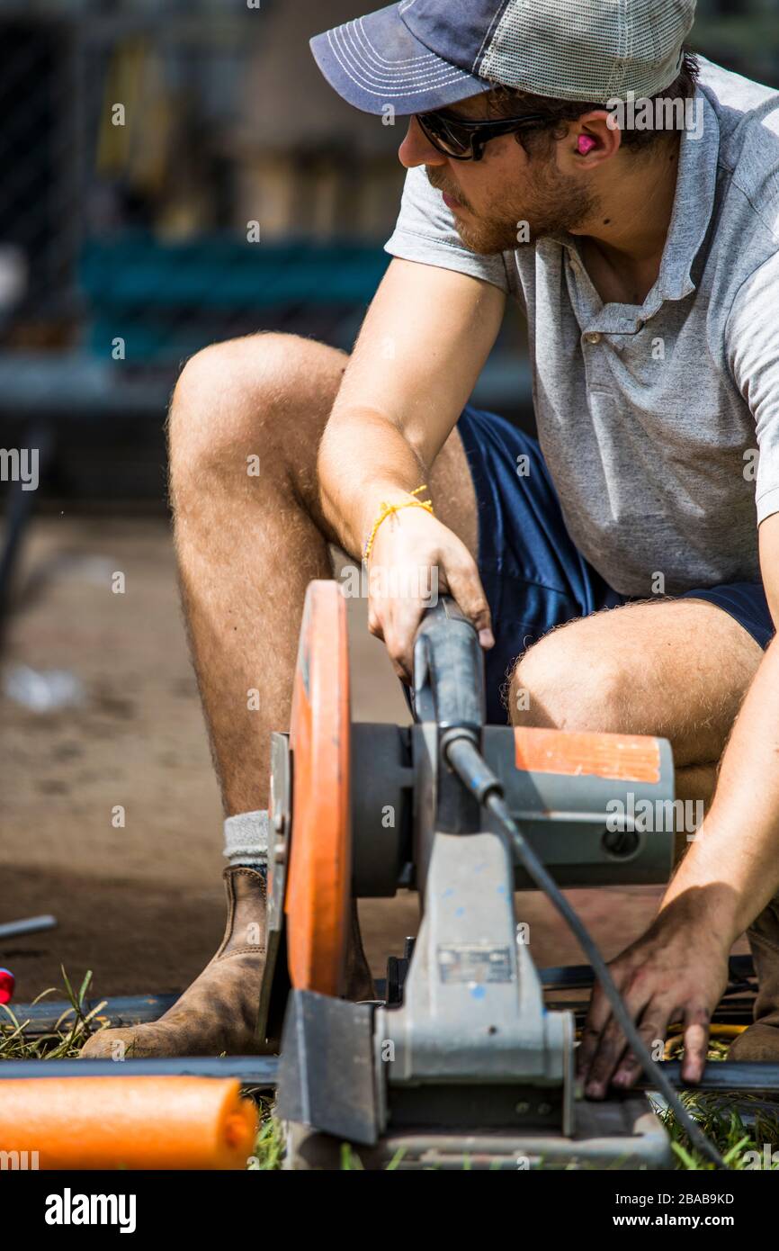 Nahaufnahme eines Facharbeiters, der mit der Hacksäge Stahl schneidet. Stockfoto