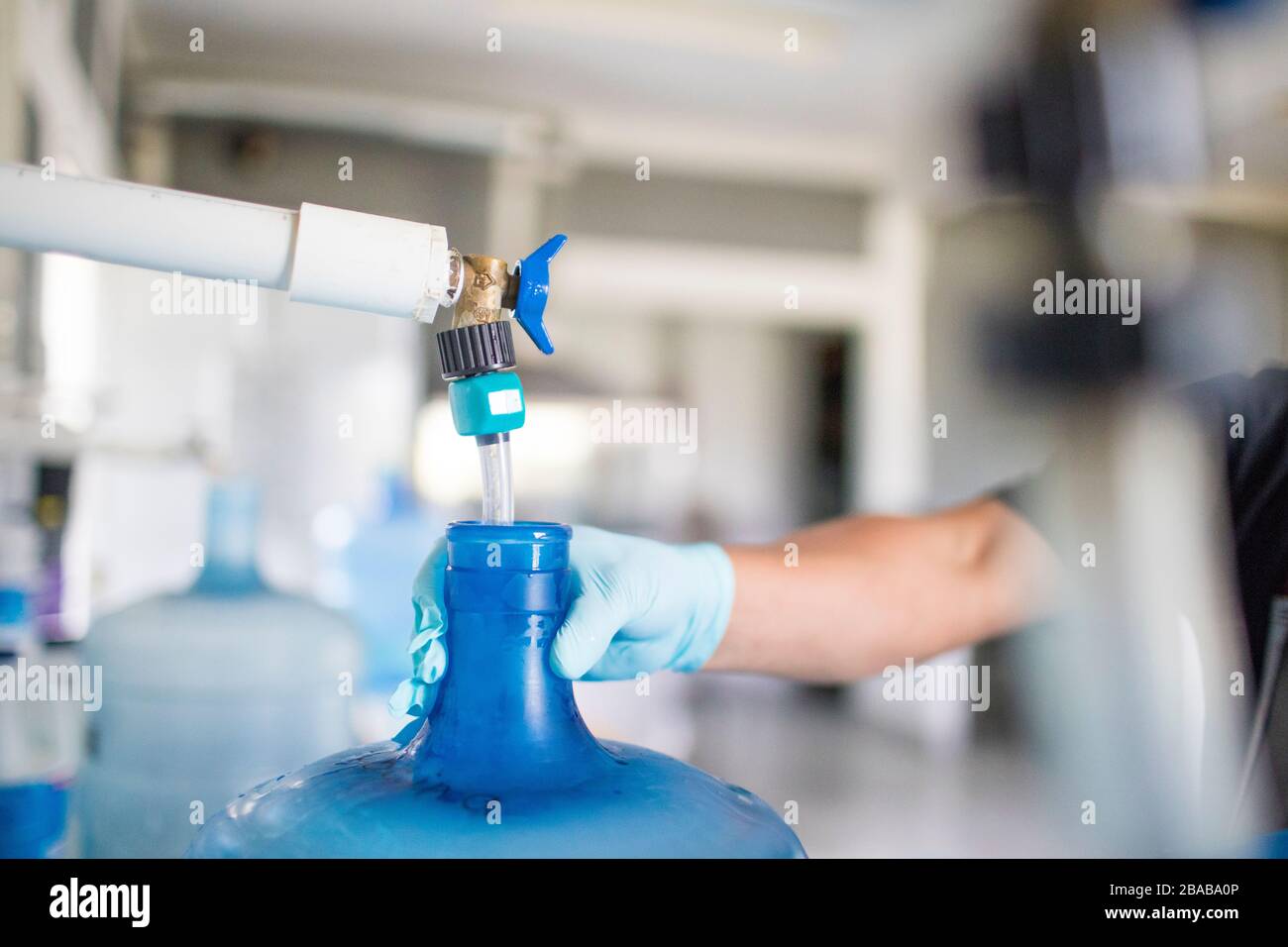 Arbeiter hält oben auf der Wasserkanne, während sie mit Trinkwasser gefüllt. Stockfoto