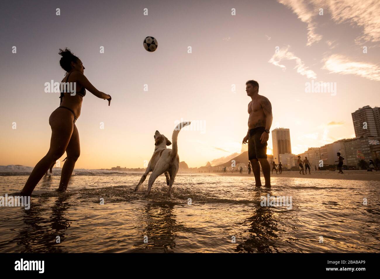 Ein Paar spielt Fußball mit Hund am Strand von Copacabana Stockfoto