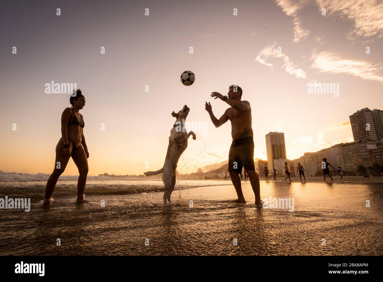 Ein Paar spielt Fußball mit Hund am Strand von Copacabana Stockfoto