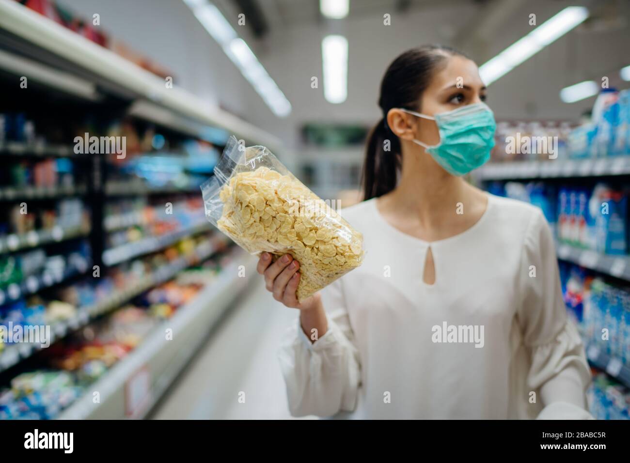 Junge Person mit Gesichtsschutzmaske kauft Lebensmittel/Vorräte im Supermarkt.Vorbereitung auf eine Pandemie-Quarantäne aufgrund von Coronavirus Covid-19 Stockfoto