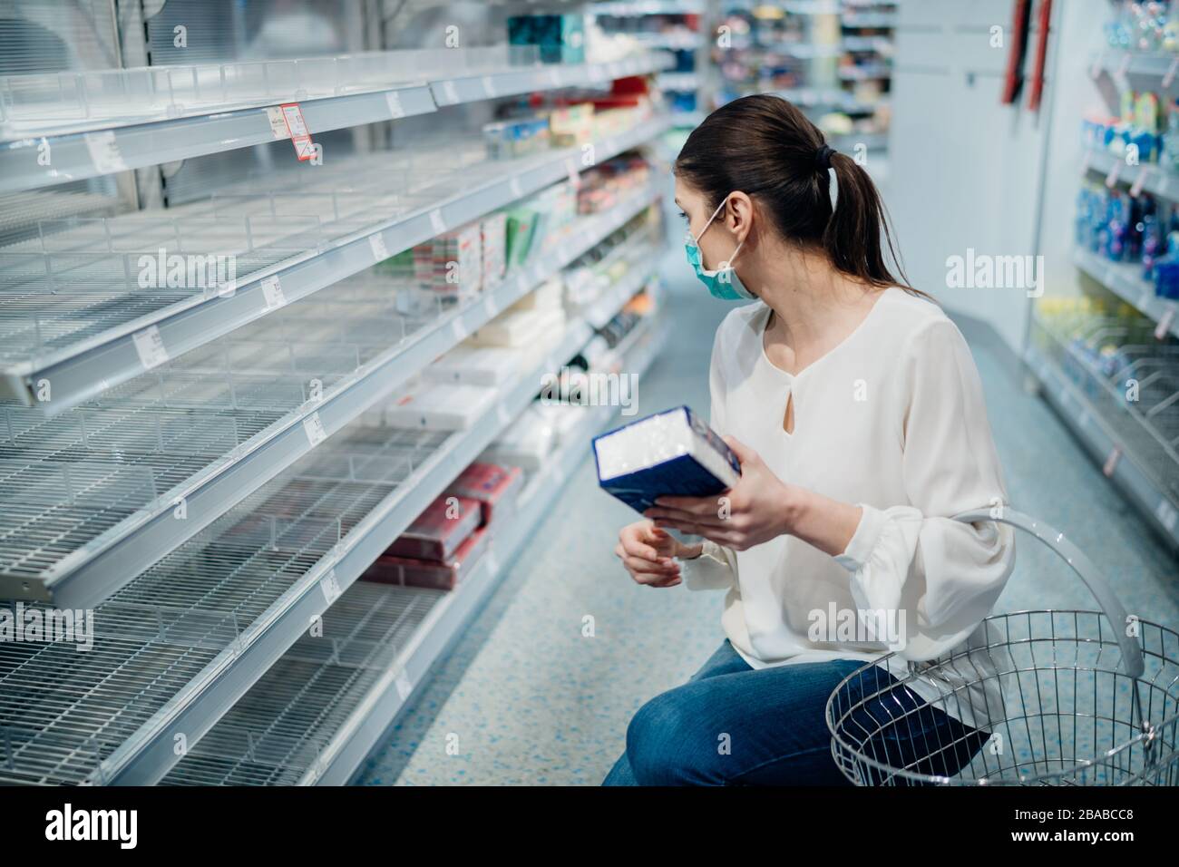 Frau trägt Gesichtsmaske, die im Supermarkt/Drogerie mit ausverkauftem Zubehör kauft.Vorbereitung für eine Pandemie-Quarantäne aufgrund von Coronavirus Covid-19 outbr Stockfoto