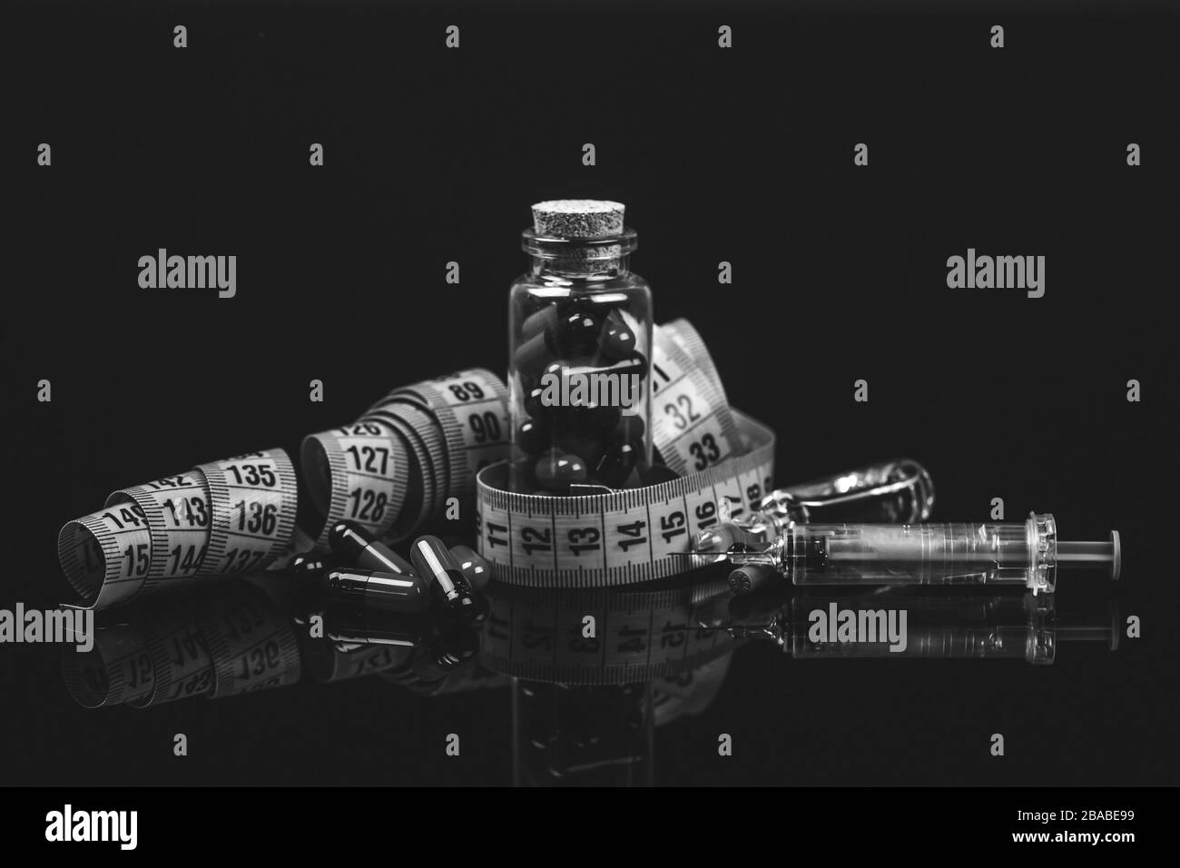 Nahaufnahme einer Glasflasche mit Diätpillen, Messbandspritze und Arznei in Ampullen. Isoliert auf schwarzem Hintergrund. - Bild Stockfoto