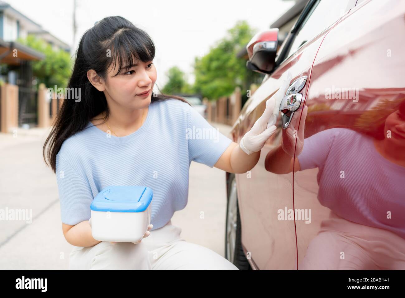 Asian Woman desinfiziert Türgriff des roten Autos mit desinfizierenden Einwegtüchern aus der Verpackung. Verhindern Sie Virus und Bakterien, verhindern Sie Kovid19, Corona VI Stockfoto