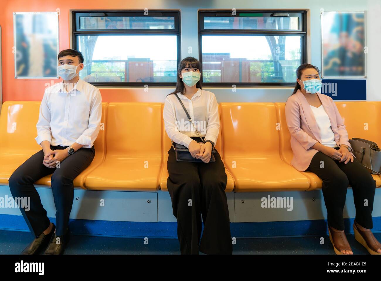 Drei Asiaten, die Maske tragen, die in U-Bahn-Entfernung für einen Sitz von anderen Personen sitzen, halten Abstand vor COVID-19-Viren und Menschen Socia Stockfoto