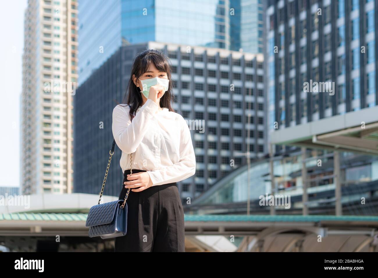 Junge asiatische Geschäftsfrau in weißem Hemd, die sich krank mit Husten fühlt, trägt Schutzmaske verhindern PM2,5 Staub, Smog, Luftverschmutzung und COVID Stockfoto