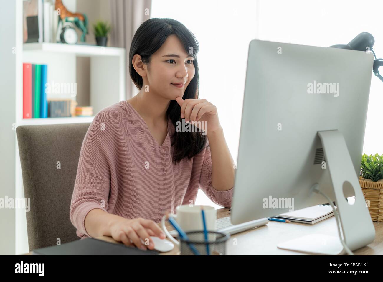 Junge asiatische Geschäftsfrau, die Computerarbeit von zu Hause aus zum Schutz von Viren verwendet und sich um ihre Gesundheit von COVID-19 kümmert. Arbeiten zu Hause und Sozialdist Stockfoto