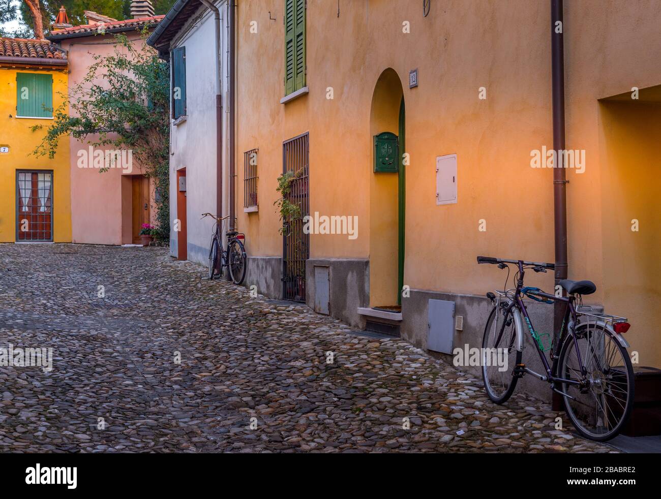 Blick auf eine ruhige mittelalterliche Innenstadt Straße mit bunten Häusern hinter den mittelalterlichen Stadtmauern von Cesena mit Kopfsteinpflaster und einem alten Fahrrad in Italien Stockfoto