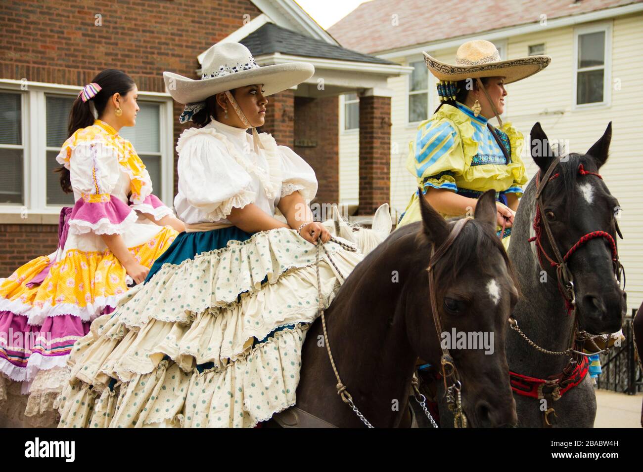 Straßenparade, Frauen in bunten Kleidern, die auf Pferden reiten, Pilsen, Chicago, Illinois, USA Stockfoto