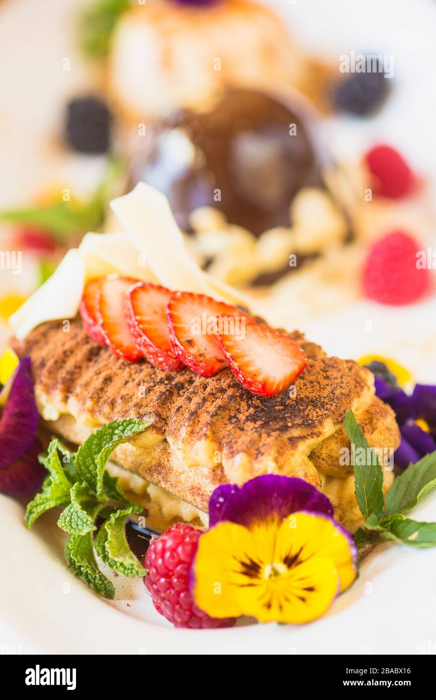 Tiramisu mit Erdbeeren und essbaren Blumen auf einer Dessertplatte Stockfoto