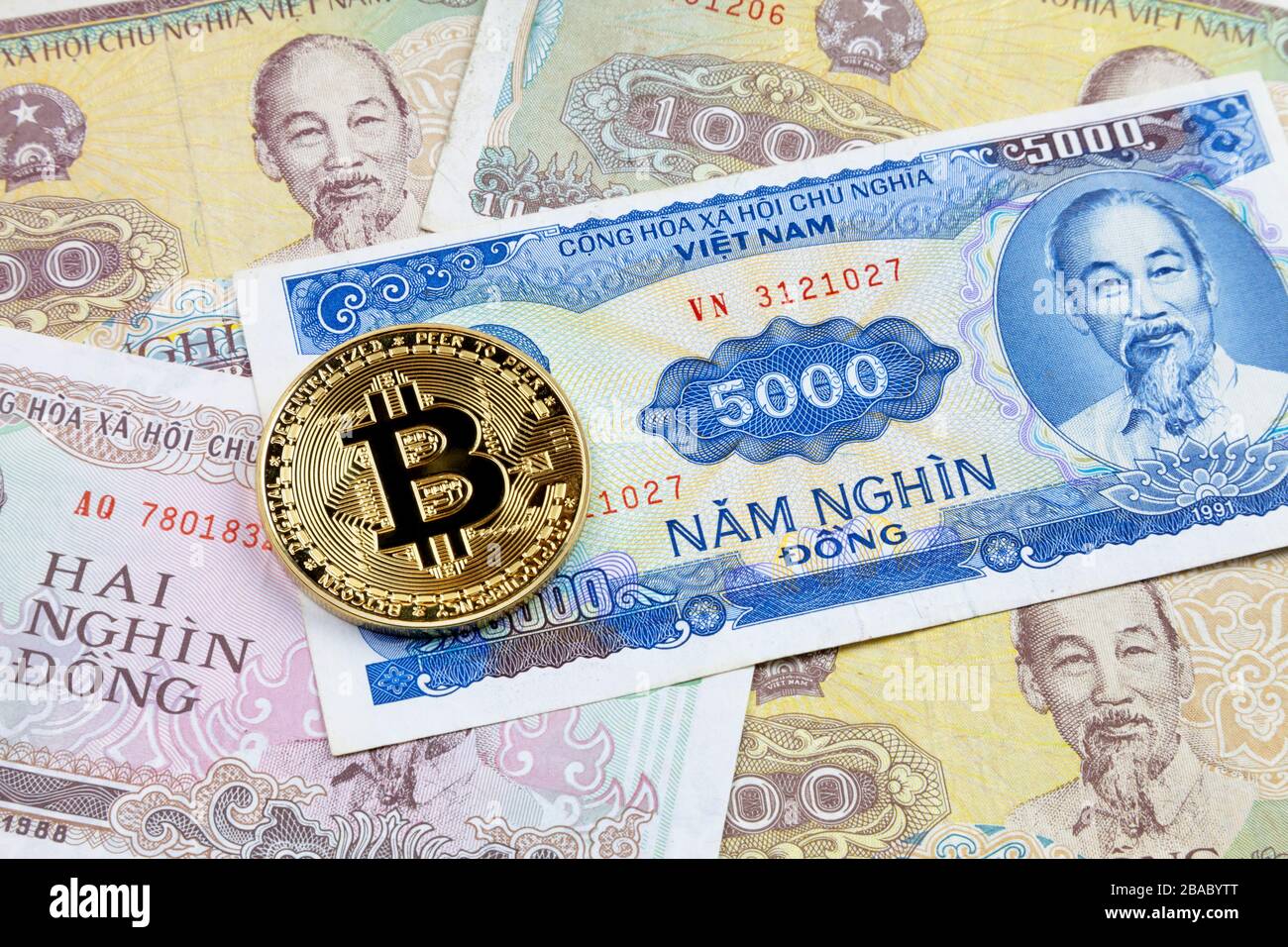 Nahaufnahme einer goldenen Bitcoin-Münze auf einem Stapel vietnamesischer Dong-Banknoten. Stockfoto