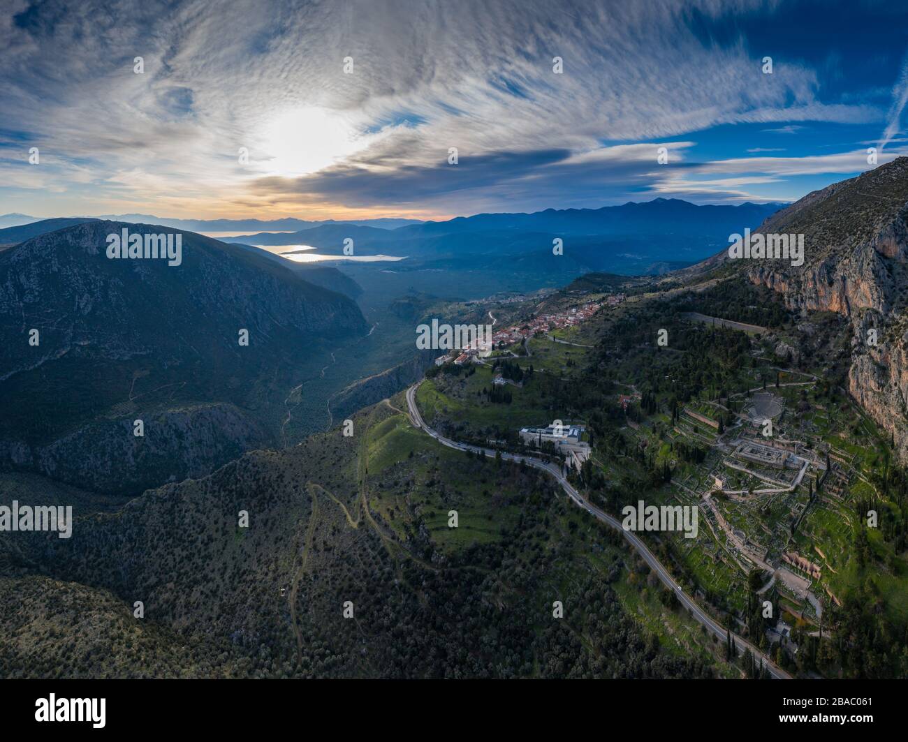 Luftaufnahme von Delphi, Griechenland, dem Golf von Korinth, orangefarbene Wolkenfarbe, Berghang mit geschichteten Hügeln darüber hinaus mit Dächern im Vordergrund Stockfoto