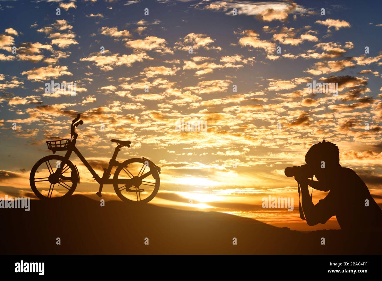 Silhouette des Fotografen, der ein Fahrrad bei Sonnenuntergang fotografiert. Stockfoto