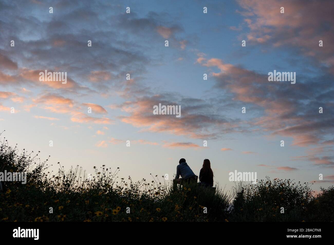 Ein Paar, das den Sonnenuntergang im Baldwin Hills Park mit Blick auf Culver City beobachtet und einen Blick vom Meer in die Innenstadt von Los Angeles, Kalifornien, bietet Stockfoto