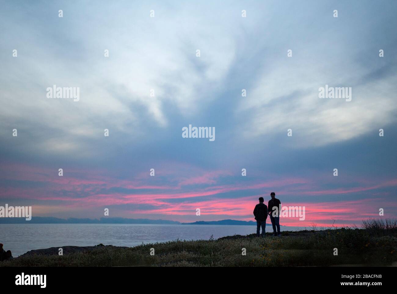 Menschen, die den Sonnenuntergang von Klippen mit Blick auf den Pazifischen Ozean in der Nähe von Malibu, Kalifornien, beobachten. Stockfoto